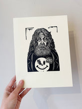 Load image into Gallery viewer, Hand holding a print of a stylized illustration of Alan Moore with long hair and a beard, wearing a jacket with a smiley face design.